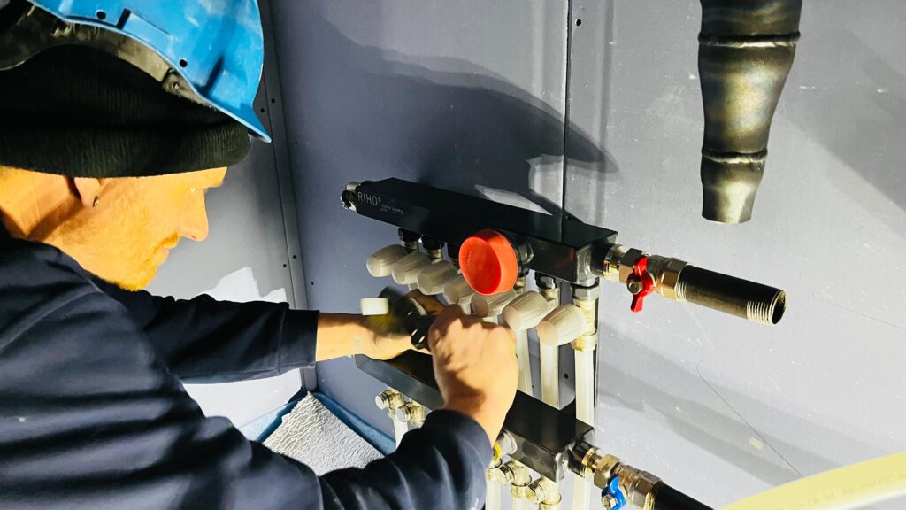 Vloerverwarming monteur sluit verdeler aan